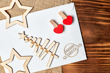 Wall Mural - New Year Flatlay on burlap and wooden background made of envelope, Christmas tree, stars and clothespins with hearts. Close-up