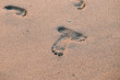 Two footprints barefoot in the desert sand. Texture the surface light sand dune. Concept of honeymoon and walking on the summer beach