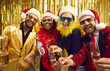 © Studio Romantic - Joyful friends in Santa hat, color bra and funny eyeglasses enjoy Christmas or New Year night celebrate x-mas noel give toast screaming looking at camera cheering wine glasses. Winter holiday party