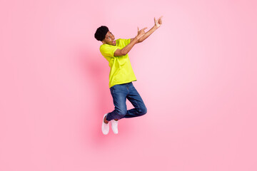 Wall Mural - Full size photo of afro american young man point finger empty space jump isolated on pink color background