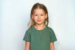© Vladimir - Portrait of a girl on a white background. Collected hair and green T-shirt. Cute smile happy smile. A cheerful and serious child looks at the camera. place for text.