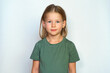 © Vladimir - Portrait of a girl on a white background. Collected hair and green T-shirt. Cute smile happy smile. A cheerful and serious child looks at the camera. place for text.