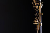 Fototapeta Krajobraz - Part of a clarinet with gold plated keys on a black background. A woodwind instrument common to classical music.