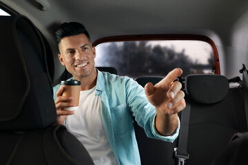 Wall Mural - Man with cup of drink in modern taxi