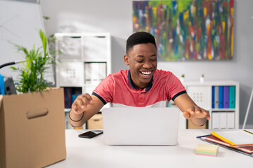 Wall Mural - Handsome teenager sits at desk at home with laptop, next to phone and documents, boy won computer game, money, bet, he is happy, laughing, joyful, slaps hands on desk from happiness