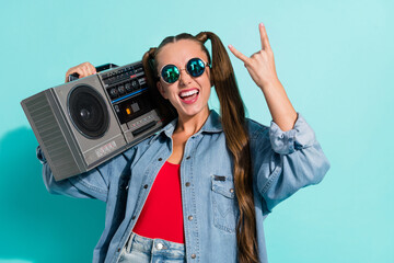 Canvas Print - Photo of attractive beautiful woman dressed denim jacket dark glasses listening boom box showing rock sign isolated teal color background