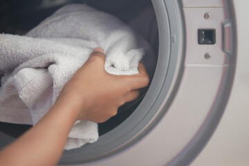 putting towel and cloths in a washing machine.