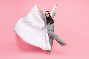 Full length photo of sweet charming lady sleepwear mask holding flying blanket walking smiling isolated pink color background