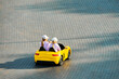 © TRAVELARIUM - Two little girls driving toy car. Battery vehicle with remote control for children entertainment
