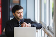 © eakgrungenerd - handsome businessman looking wristwatch with laptop. checking work time.