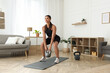 © New Africa - Young woman exercising with kettlebell at home