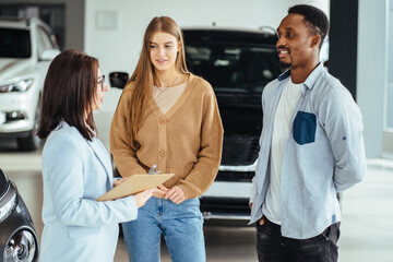 Canvas Print - Female seller working with multiracial couple at auto center