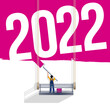 Carte de vœux pour les jeunes entreprises énergiques, avec un peintre sur son échafaudage qui peint un mur en rose vif en laissant apparaître 2022.