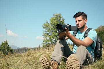 Wall Mural - Professional photographer taking picture with modern camera in mountains. Space for text