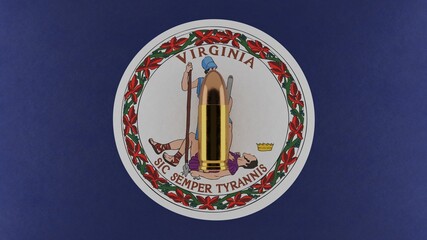 Top down view of a 9mm bullet in the center and on top of the US state flag of Virginia