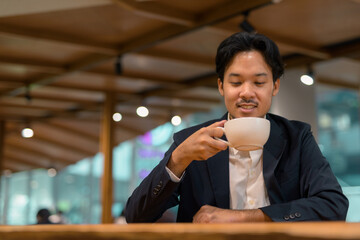 Wall Mural - Portrait of Asian businessman in coffee shop drinking coffee