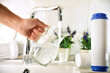 Leinwandbild Motiv Hand filling jug from a tap with filtered osmosis water