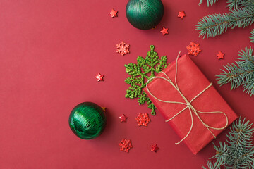 Wall Mural - Flat lay frame with fir branches, christmas baubles decoration and gift box on a red background