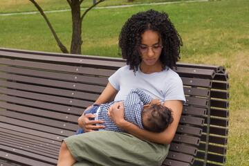 Young mother breast-feeds her baby in the park