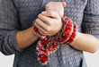 © Наталья Микулич - The hands of a young girl are tied with a red decorative Christmas garland. The red tinsel for the Christmas tree is wrapped around the hands of a young girl. Holiday addiction. Holiday embezzlement