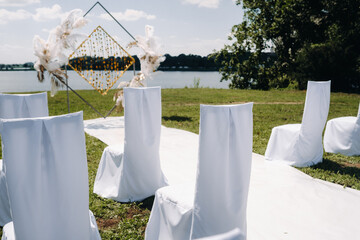 Wall Mural - Decorated wedding arch in nature.Wedding ceremony with an arch decorated with retro-style feathers on a lake background