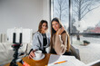 © Andrii - Two young beautiful girls are sitting in a cafe, recording video blogs and communicating on social networks.