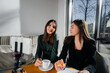 © Andrii - Two young beautiful girls are sitting in a cafe, recording video blogs and communicating on social networks.