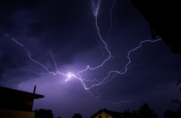 Poster - Closeup of lightning strikes in a dark night sky over a village