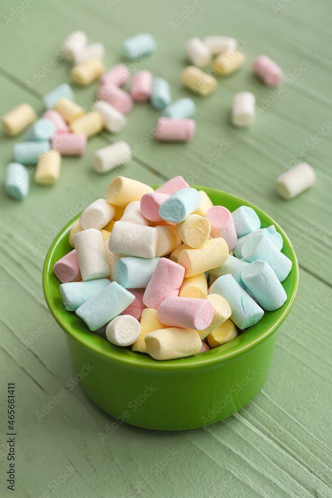 Ramekin with tasty marshmallows on color wooden background, closeup