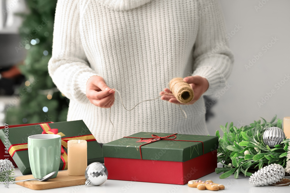 Woman decorating Christmas gift box at home, closeup