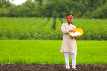 Sticker - Indian farmer spreading fertilizer in the green agriculture field.