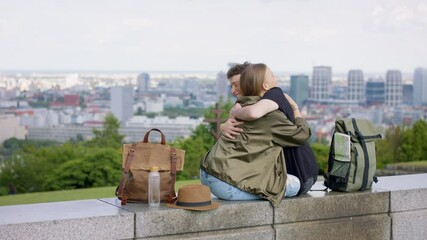 Wall Mural - Young couple travelers in city on holiday, hugging. Cityscape in the background.