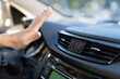 Female hand checking air conditioning panel inside car. Woman driver suffer from heat in vehicle holding hand at conditioning system cooling grid. Hot summer season and driving automobile concept