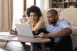 © fizkes - Concentrated young african american married couple looking at computer screen, analyzing household budget, paying bills in e-banking app, planning investment or managing budget together at home.