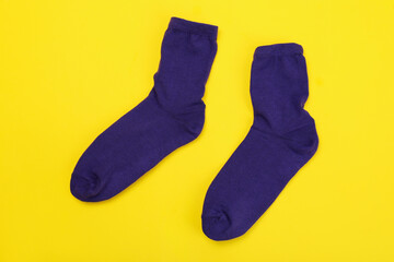 Wall Mural - Pair of violet socks on yellow background