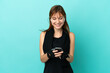 © luismolinero - Redhead sport girl isolated on blue background sending a message with the mobile