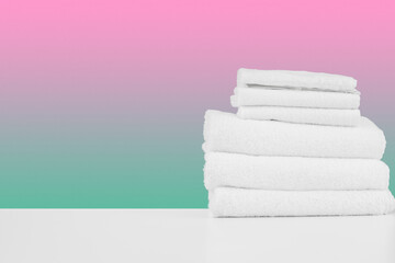 Wall Mural - Stacked clean towels on white table against color background