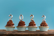 Christmas Greeting Card With Chocolate Cupcakes And 2022 Candles On Blue Background. New Year 2022