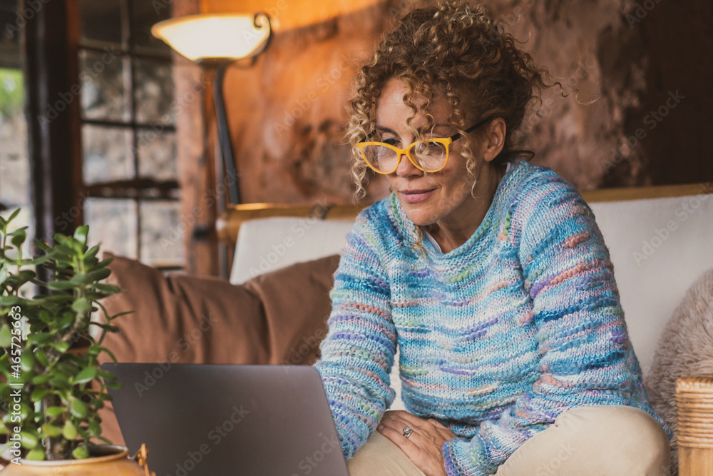 Portrait of happy modern woman at home sitting on the sofa using ...