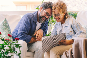 Happy and cheerful man and woman reading together a notebook outside at home. Enjoyed caucasian couple takes notes and read with smile. Adults people at home