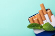 Pack of menthol cigarettes and mint on turquoise background, top view. Space for text