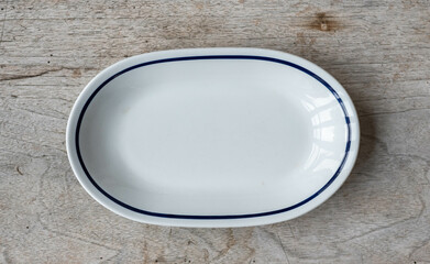 Vintage porcelain plate with a blue stripe - on a rustic wooden table