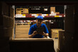 Young worker in blue uniform checklist manage parcel box product in warehouse. Asian man employee using tablet working at store industry. Logistic import export concept.