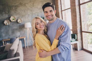 Poster - Photo of beautiful shiny young lovers dressed casual clothes hugging smiling indoors apartment