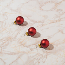 Minimal Christmas Composition With Three Red Baubles On Marble Background. Creative New Year Concept With Copy Space.