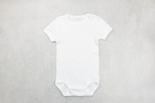 White Baby Girl Or Boy Bodysuit Mockup Flat Lay On The Gray Concrete Background. Design Onesie Template, Print Presentation Mock Up. Top View. 
