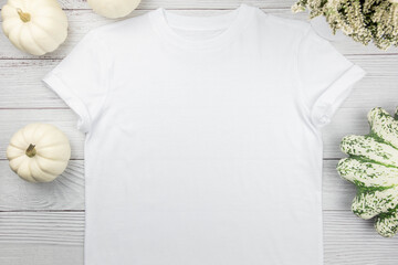 White womens cotton t-shirt mockup with pumpkins on white wooden background. Design t shirt template, print presentation mock up. Top view flat lay.