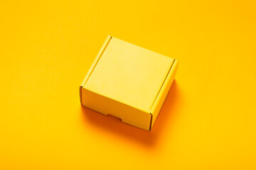 Wall Mural - Simple yellow cardboard box on color background, top view