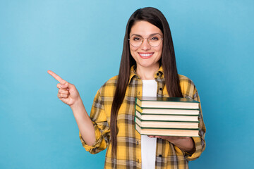 Canvas Print - Portrait of attractive cheerful girl holding book library demonstrating copy space isolated over bright blue color background