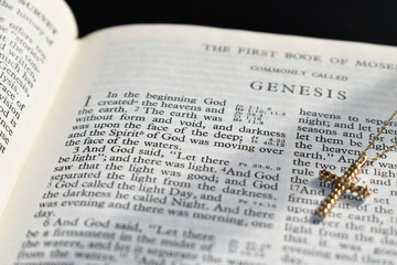 Book of Genesis with a gold cross. In the beginning God created 